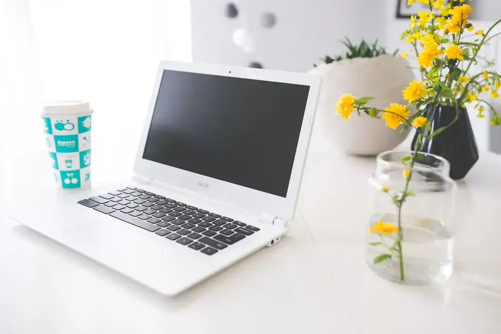 Fresh coffee and a laptop on a bright wooden desk
